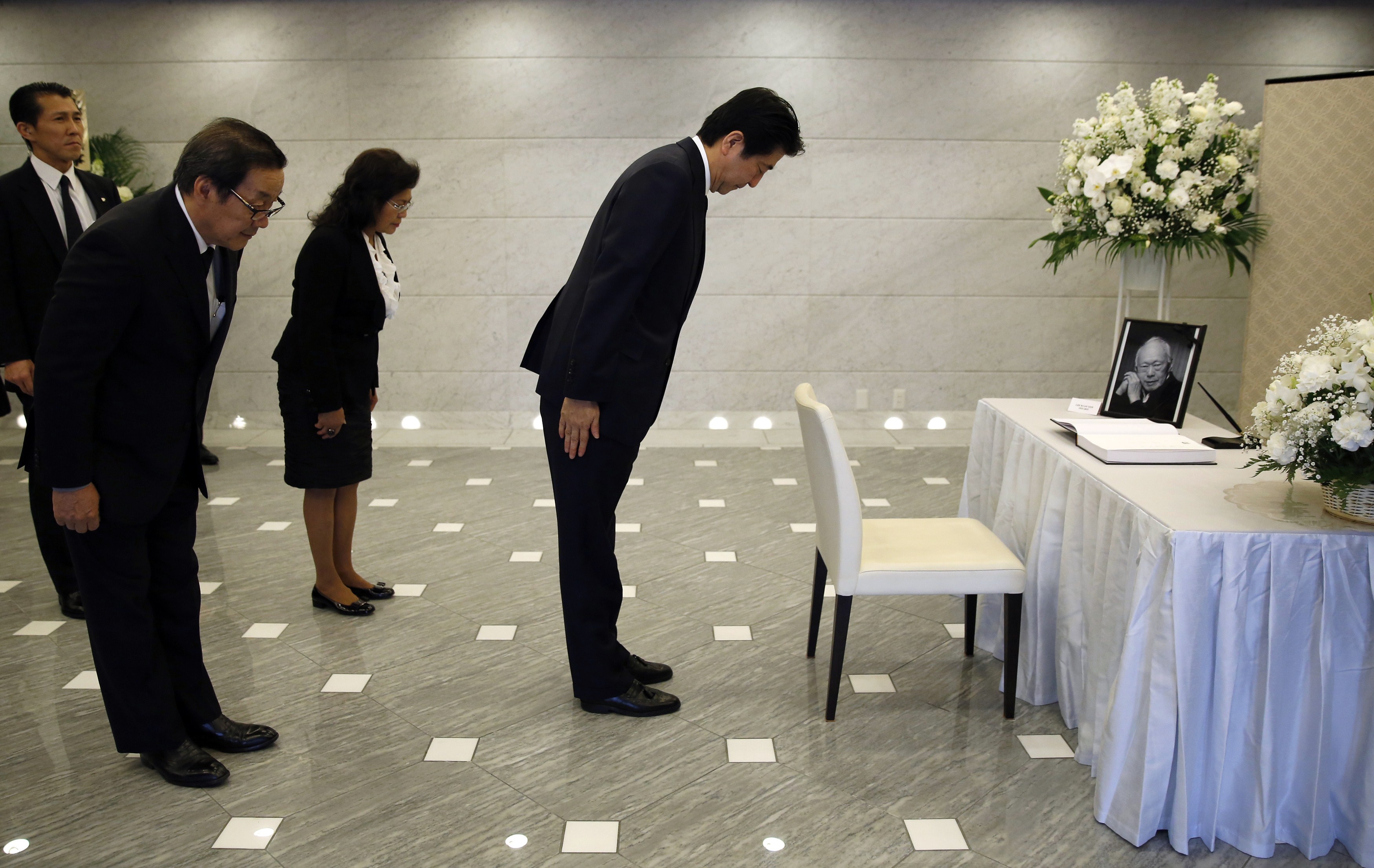 Japan's Prime Minister Shinzo Abe (R) bows with Singapore Ambassador to Japan Chin Siat Yoon (front L) and his wife Wang Lee Moi (3rd R) after signing a condolence book for the late former Singapore prime minister Lee Kuan Yew at the Singapore Embassy in Tokyo on March 24, 2015. Singapore's first prime minister Lee Kuan Yew, one of the towering figures of post-colonial Asian politics, died at the age of 91 on March 23. AFP PHOTO / POOL / Toru Hanai (Photo credit should read TORU HANAI/AFP/Getty Images)