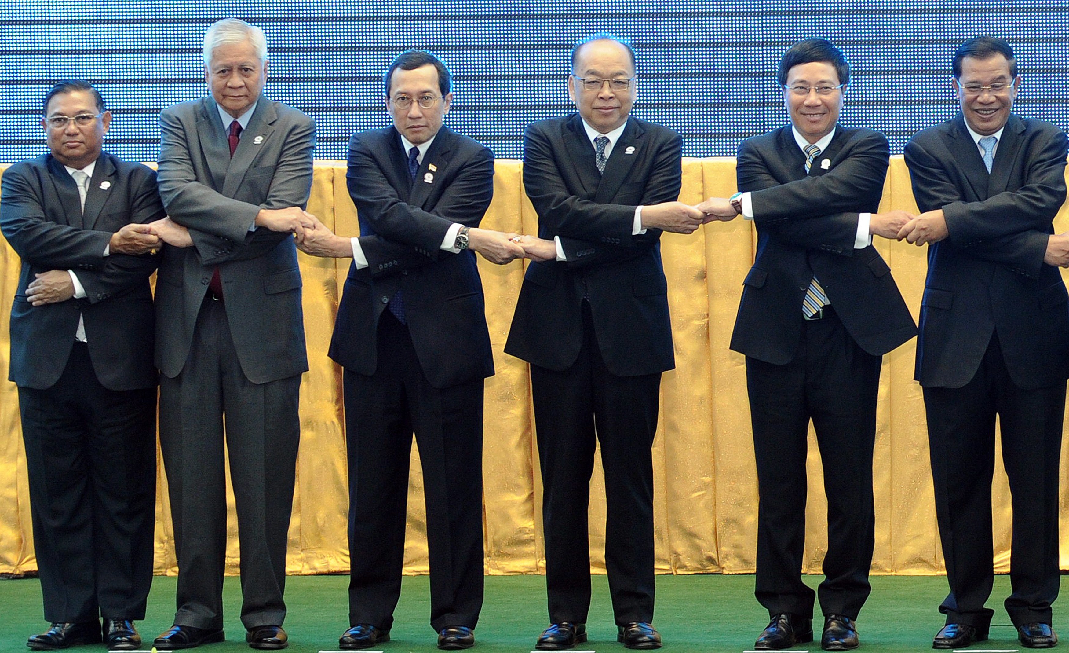 Association of Southeast Asian Nations (ASEAN) Foreign Ministers (L-R), Myanmar's Foreign Minister Wunna Maung Lwin, Philippines Foreign Secretary Albert Rosario, Singapore's Foreign Ministry Permanent Secretary Bilahari Kausikan, Thailand's Minister of Foreign Affairs Surapong Tovichakchaikul, Vietnam's Foreign Minister Pham Binh Minh and Cambodia's Prime Minister Hun Sen join hands for a group photo session during the opening ceremony of the 45th Association of Southeast Asian Nations (ASEAN) Foreign Ministers' Meeting (AMM) at the Peace Palace in Phnom Penh on July 9, 2012. . AFP PHOTO / TANG CHHIN SOTHY        (Photo credit sTANG CHHIN SOTHY/AFP/GettyImages)