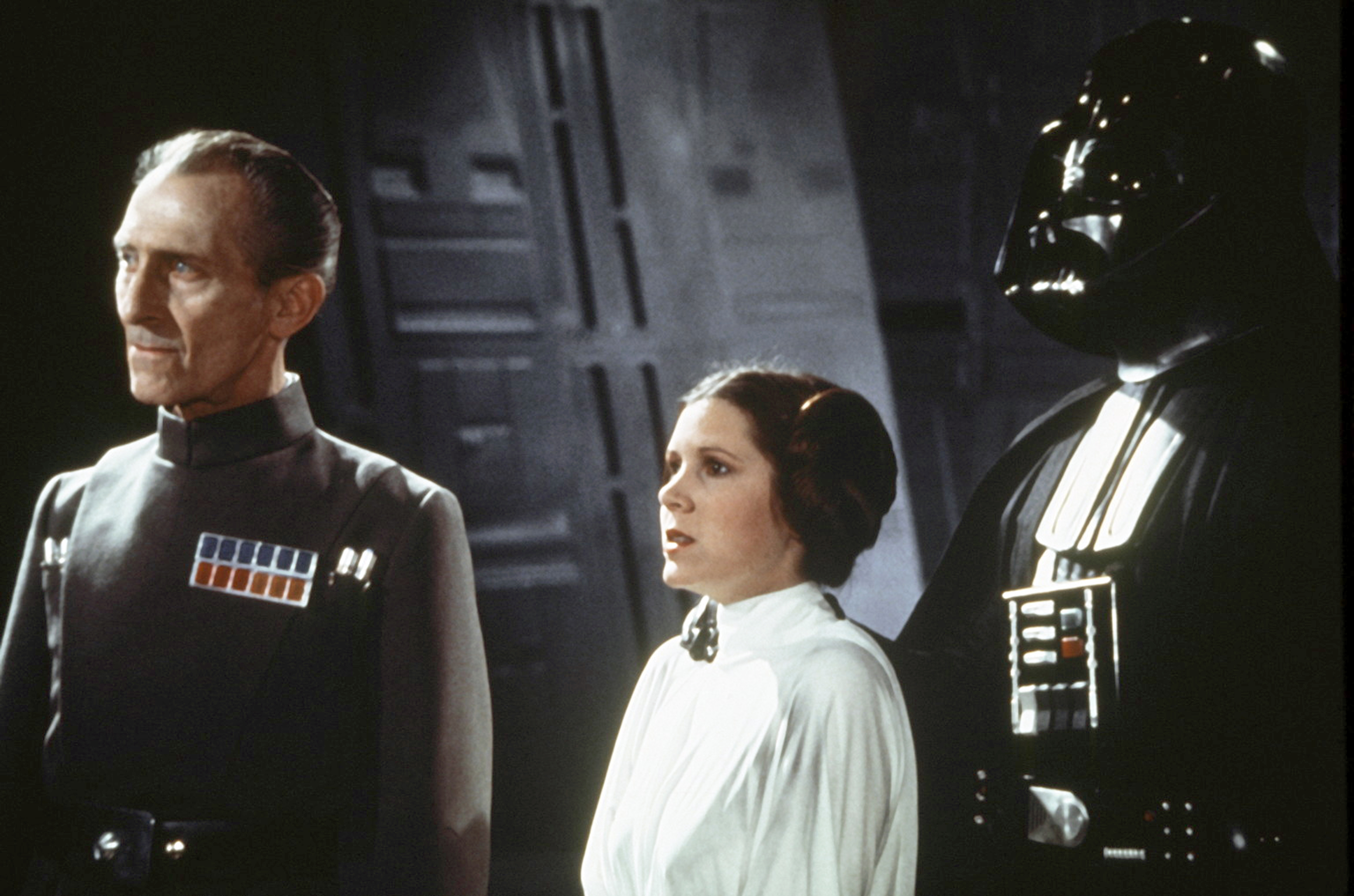 British actors Peter Cushing, David Prowse, and American actress Carrie Fisher on the set of Star Wars: Episode IV - A New Hope written, directed and produced by Georges Lucas. (Photo by Sunset Boulevard/Corbis via Getty Images)