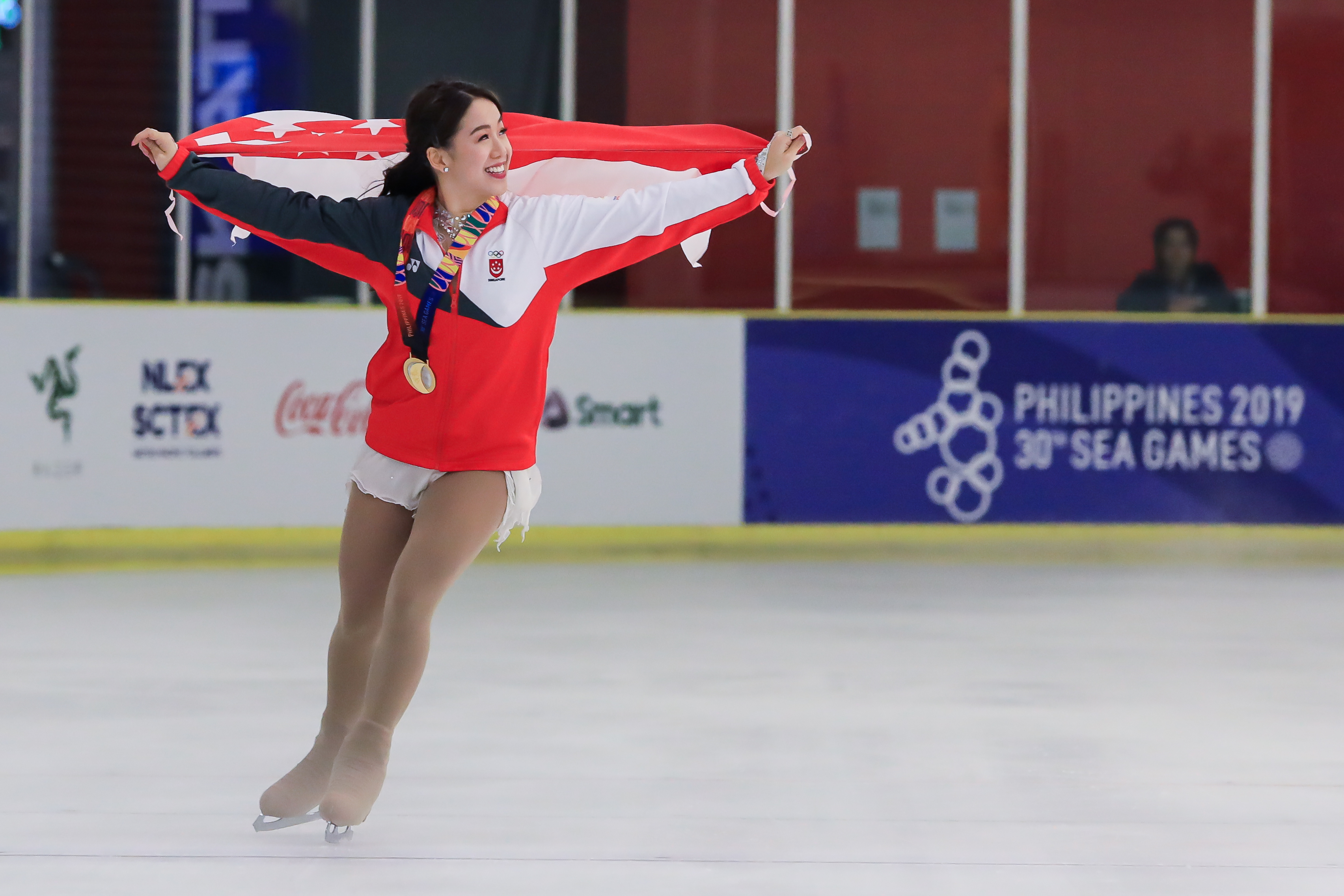 image of chloe ing skating around the rink with her gold medal and flag
