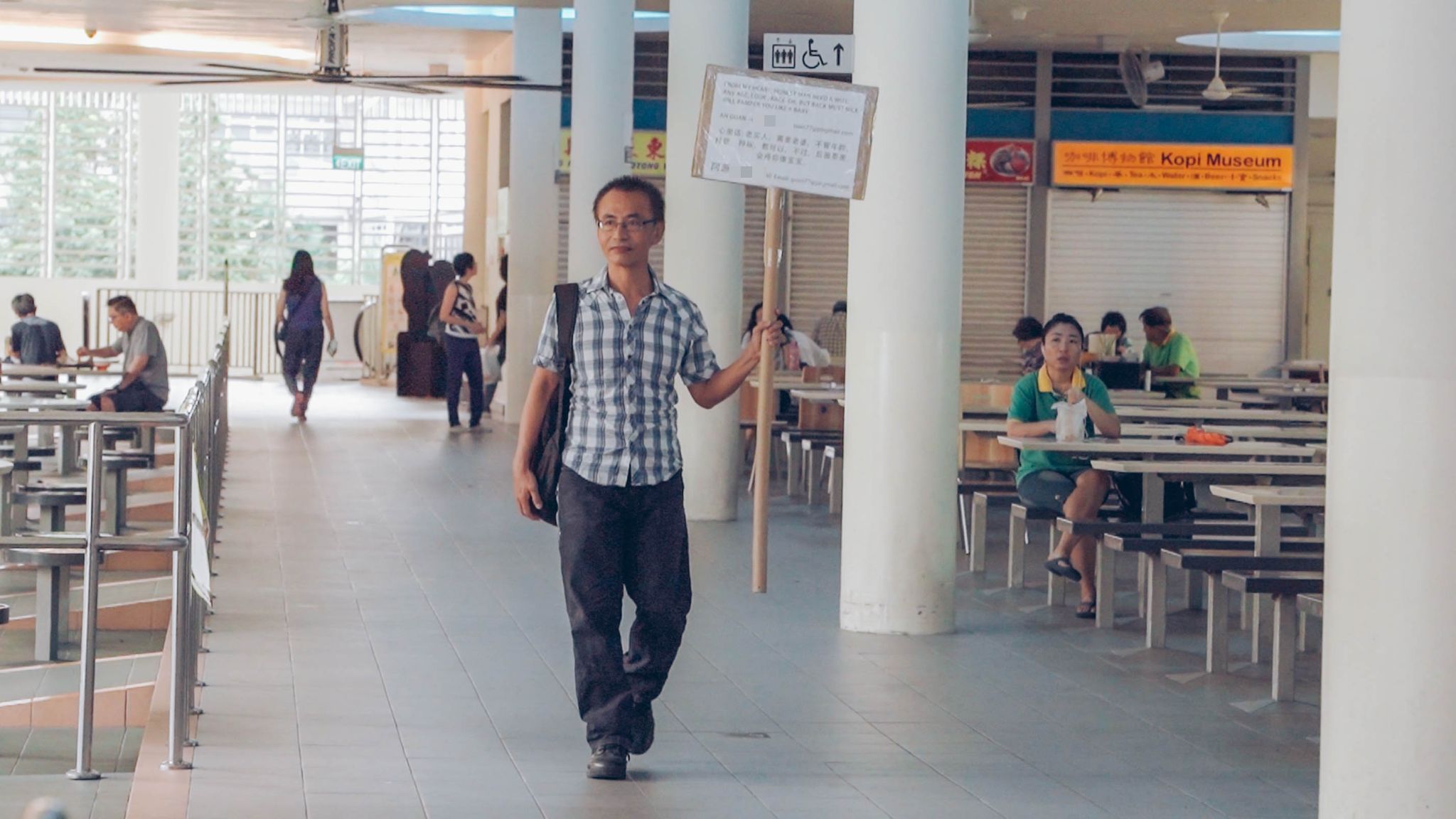 Ong Chin Guan aka Ah Guan walking with his sign