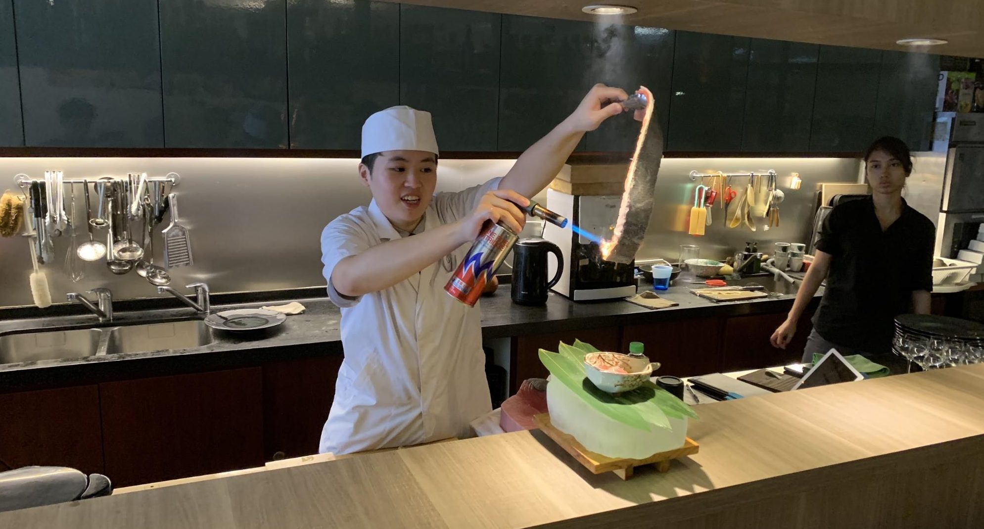 Sushi Chef Aeron Choo blowtorches a piece of fish