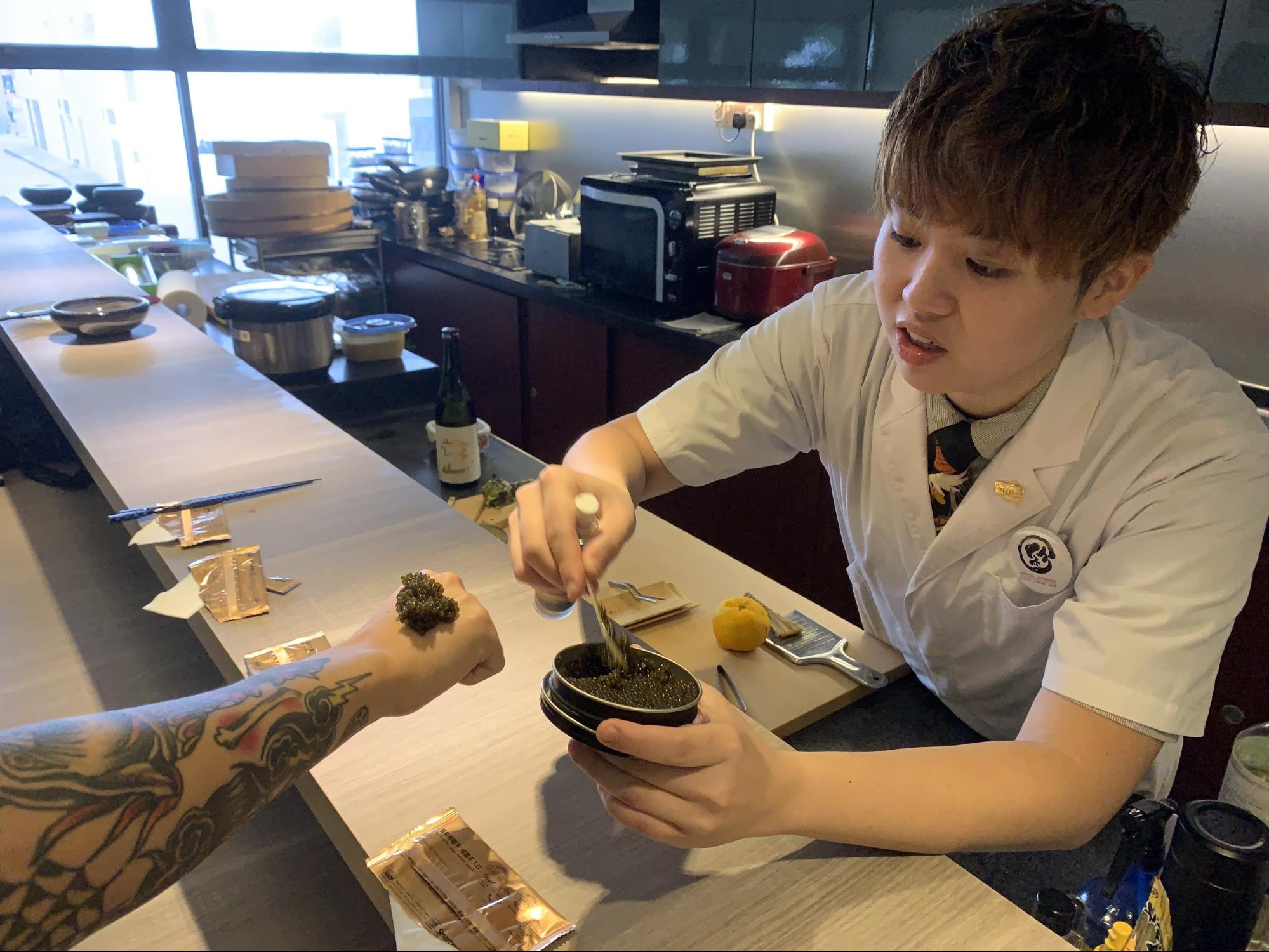 Sushi Chef Aeron Choo serving caviar onto fist