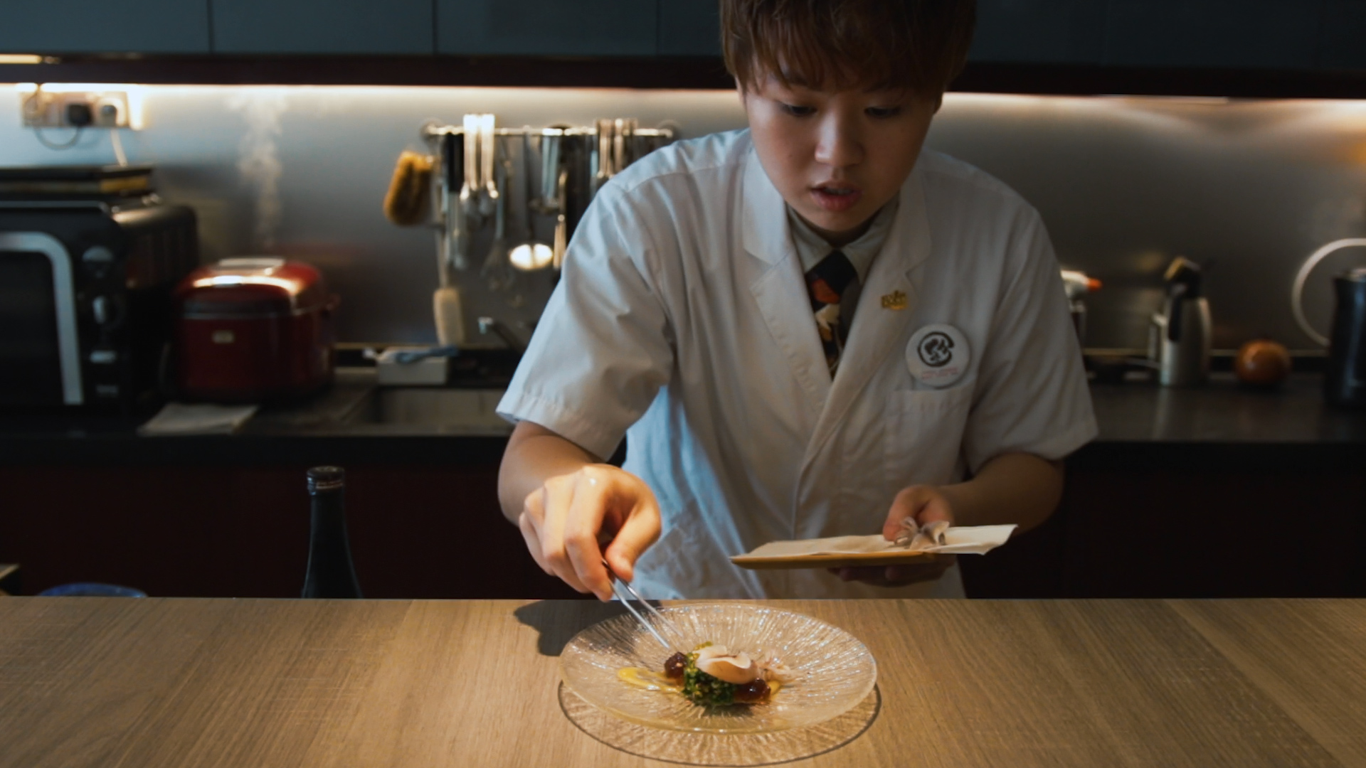 Sushi Chef Aeron Choo plates a dish over the counter