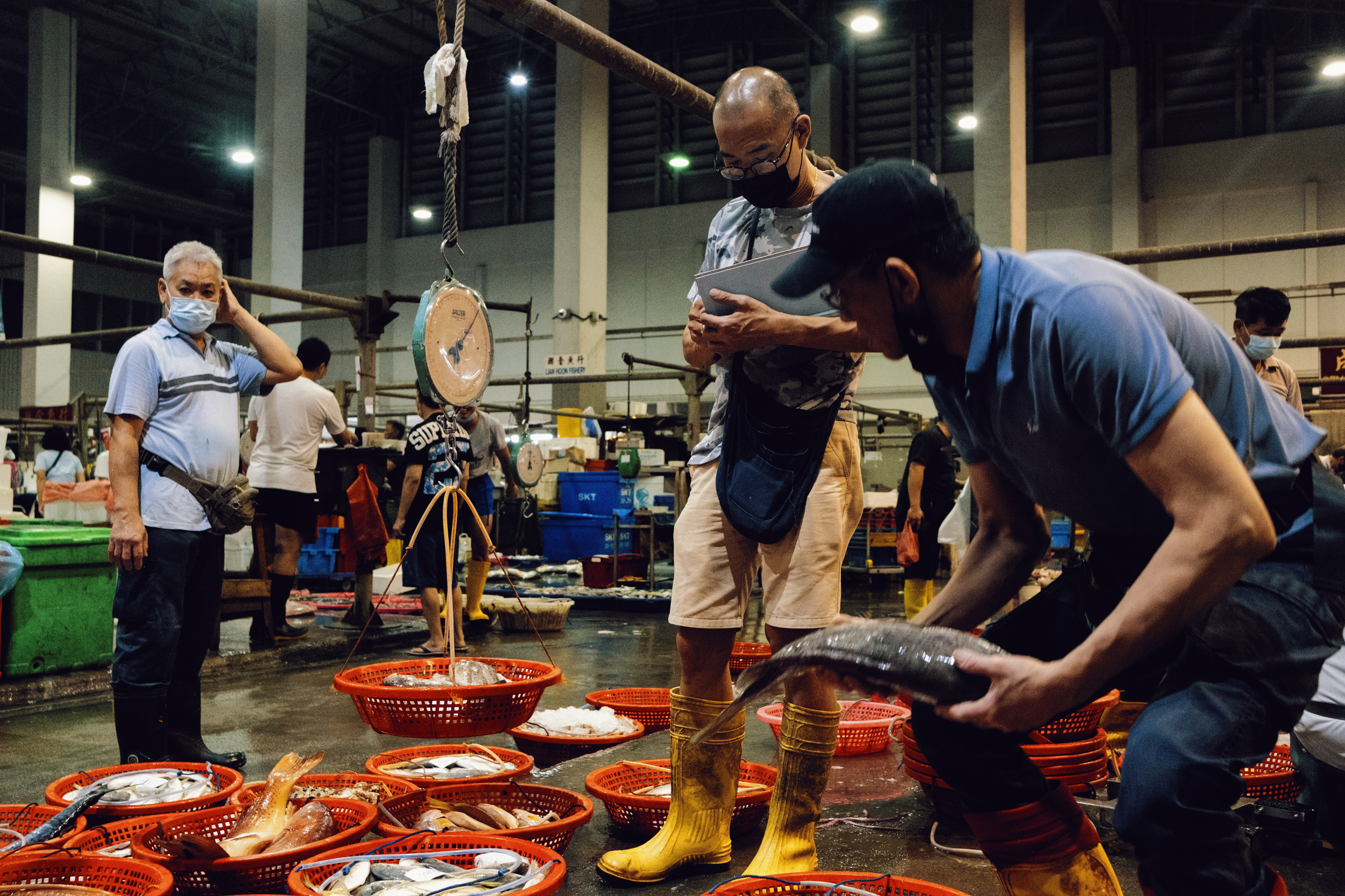 A customer brings the fish to be weighed by Goh.