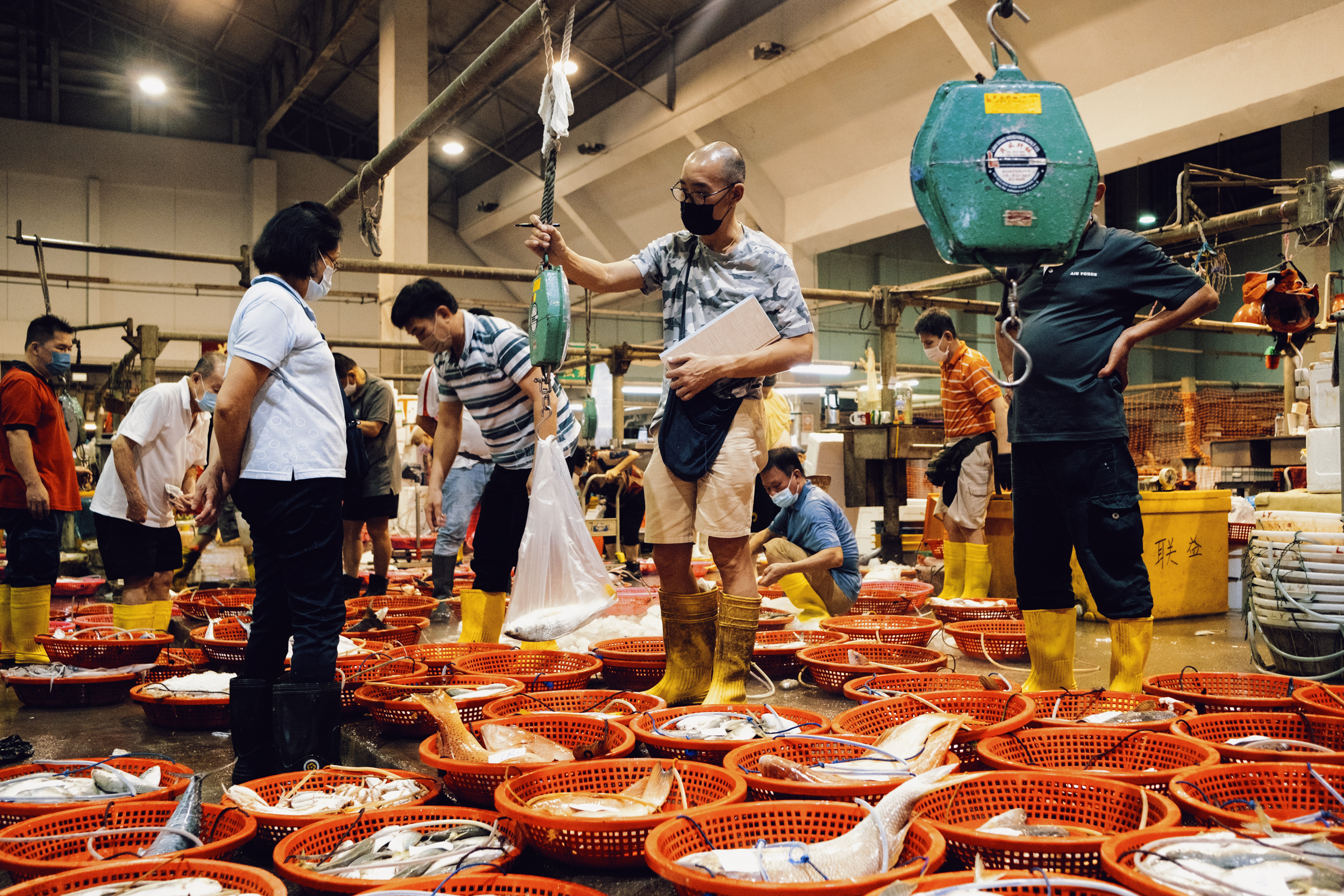 Davidson Goh stands at his weighing scale among baskets of fish.