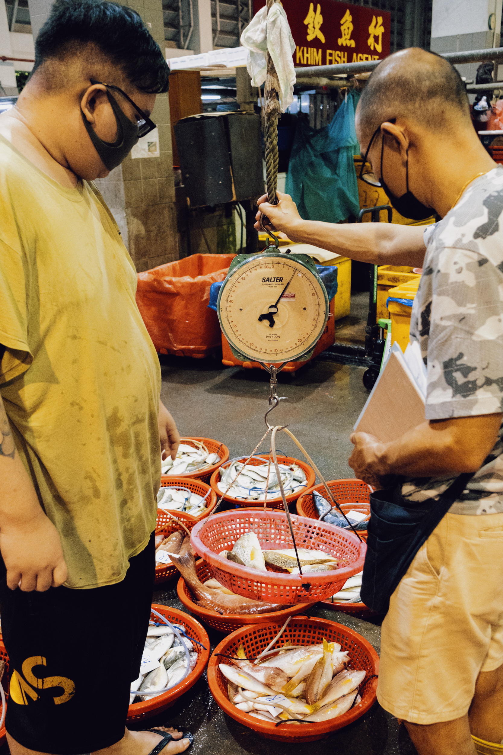 Goh and a customer weigh fish.