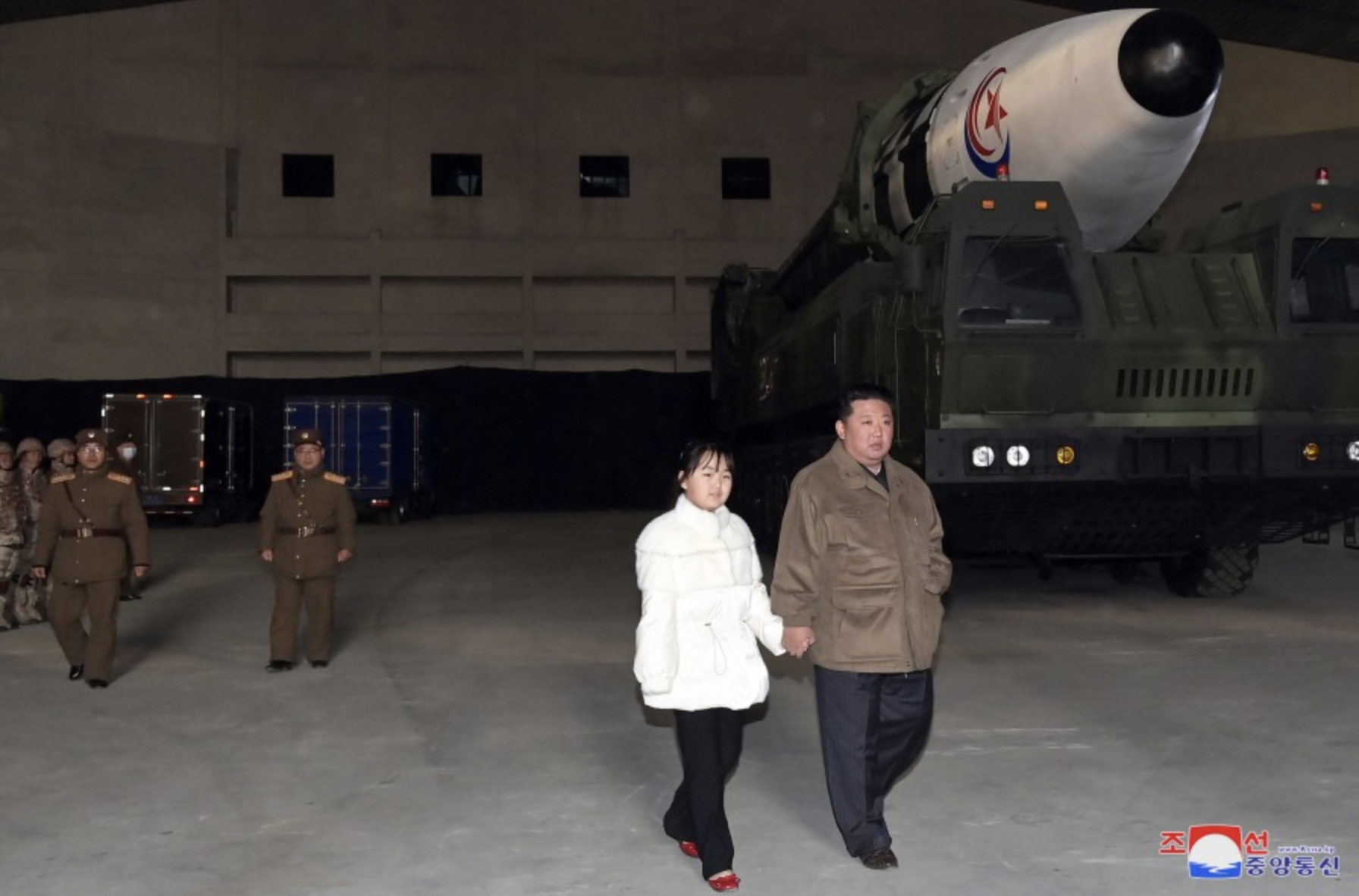 Kim and his daughter walk past the rocket.