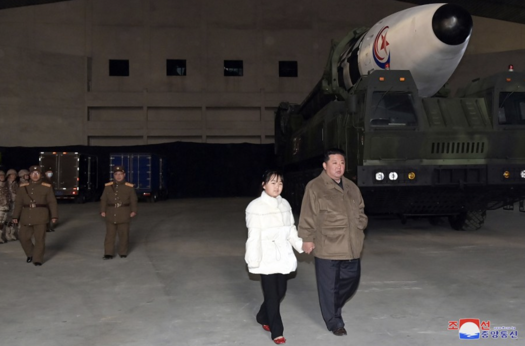 Kim and his daughter walk by the missile.