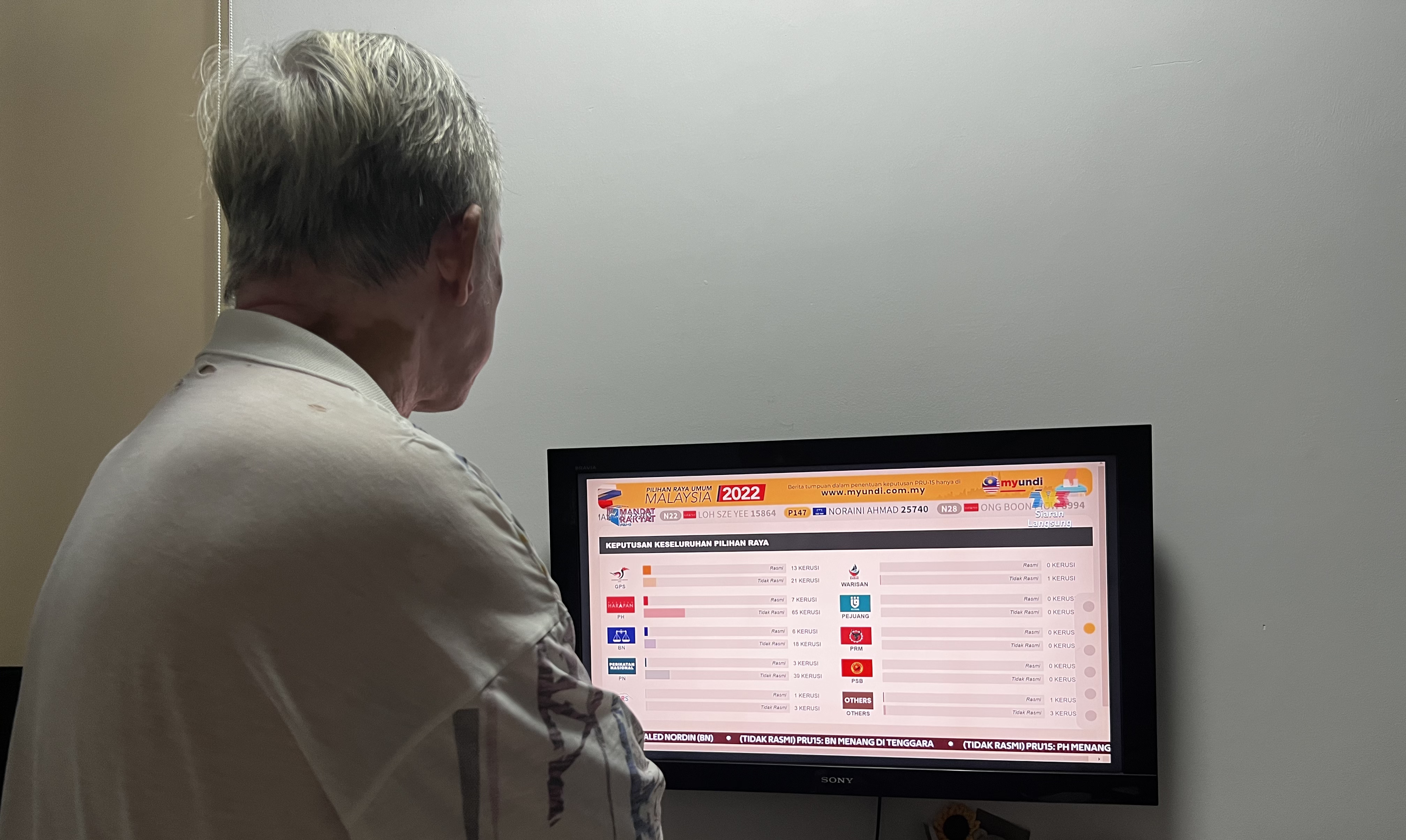 Sarah's father watches on as election results are reported on TV.