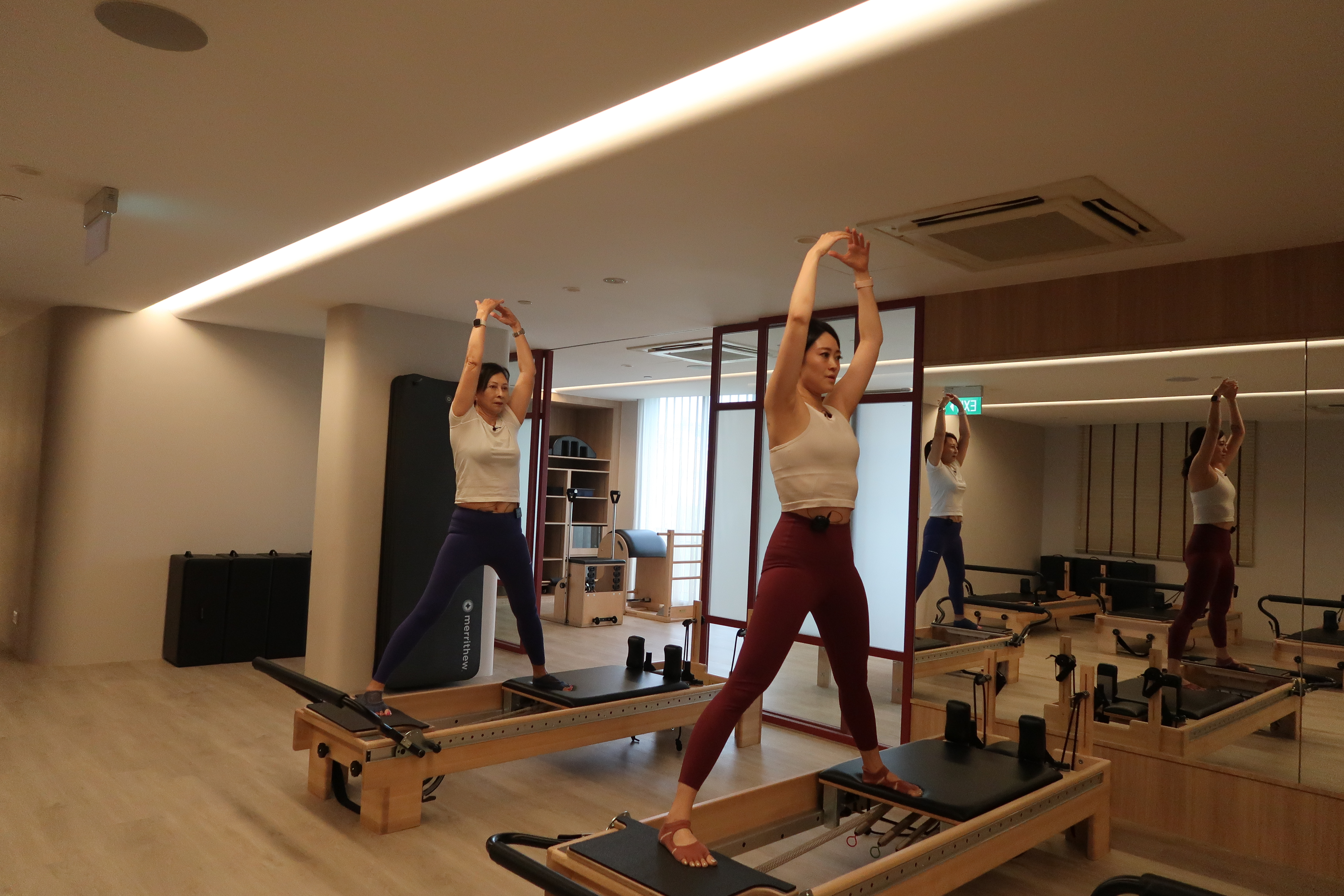 The two women using a reformer pilates machine.