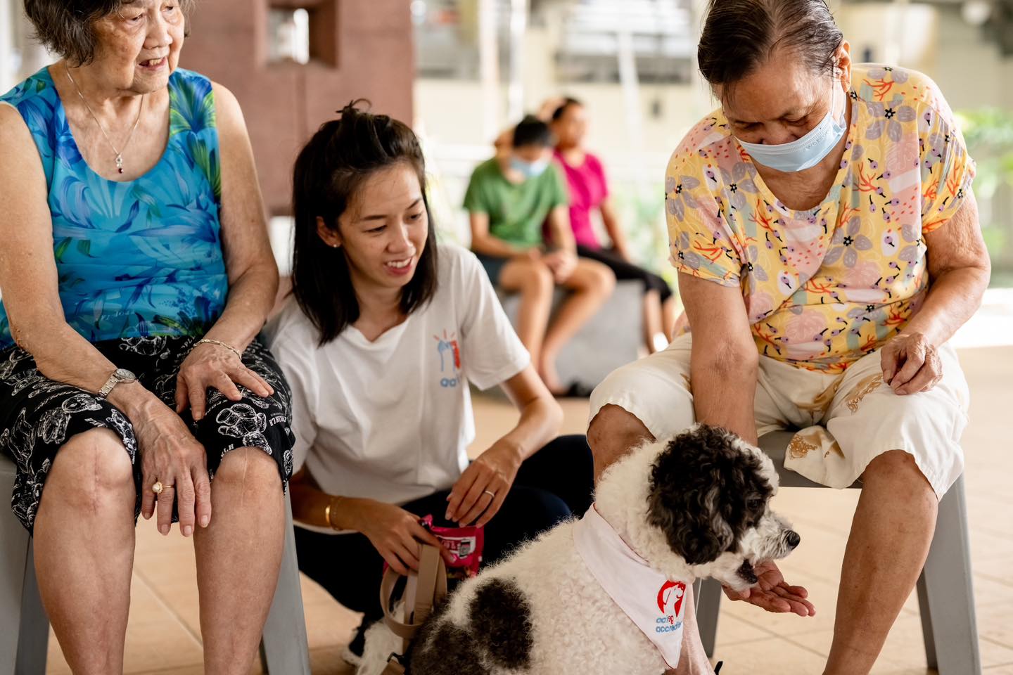 A handler sits between to residents of Care Corner with a dog.